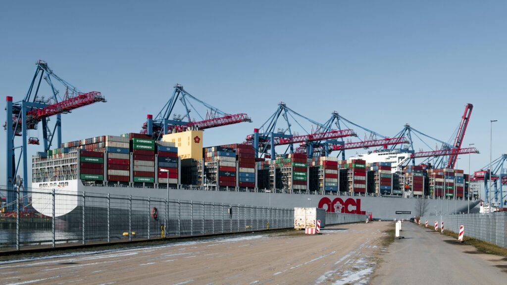 A container ship docked at a bustling shipping terminal in Hamburg, Germany.